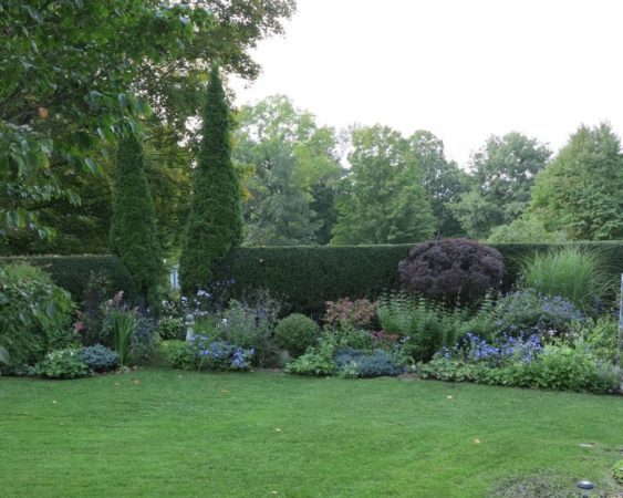 Two tall cedars act as exclamation points in this large garden, and also signal where the entrance is to the vegetable garden on the other side of the clipped hedge. (Garden Making photo)